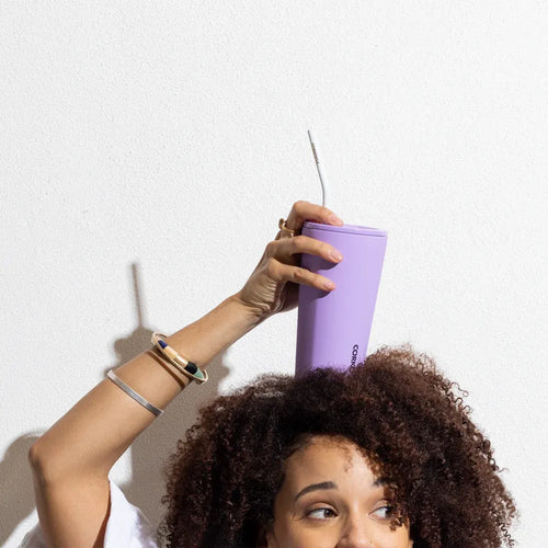 Woman holding Corkcicle tumbler with Corkcicle straw on her head.
