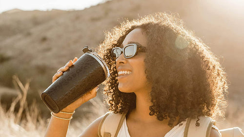 Woman drinking from Black Cheetah Print Toddy XL outside in the sun.