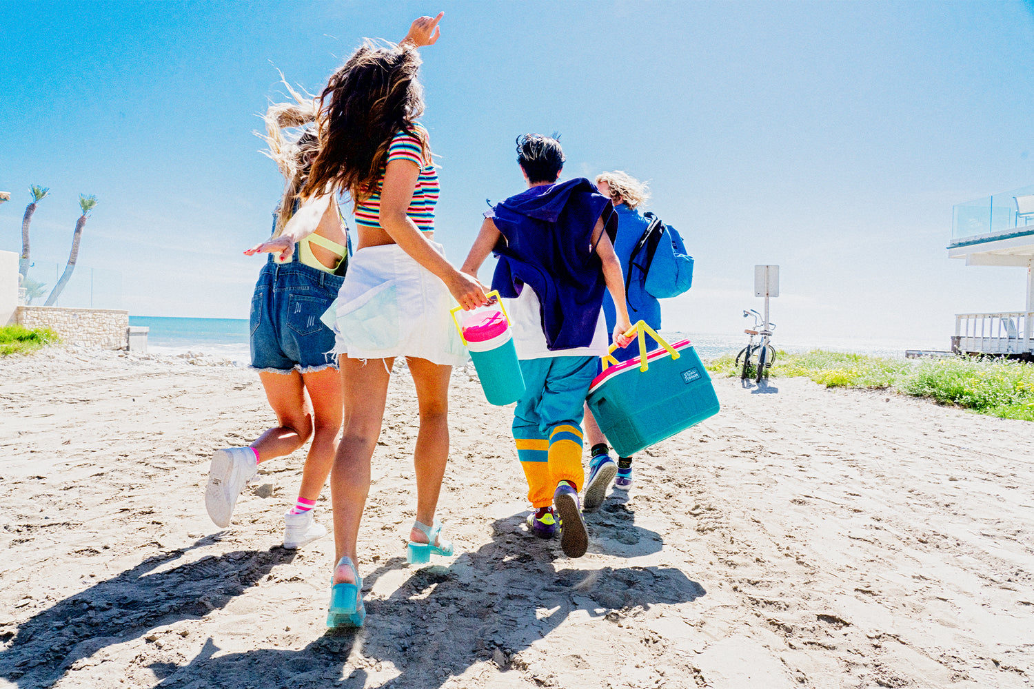 People running on the beach with Igloo half gallon jug and Igloo picnic basket cooler