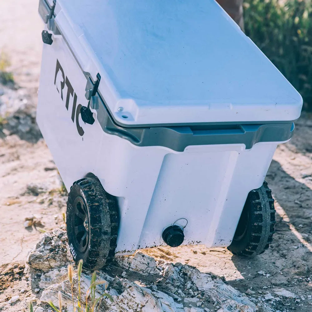 RTIC 52 quart cooler with wheels in white on sand and rocks