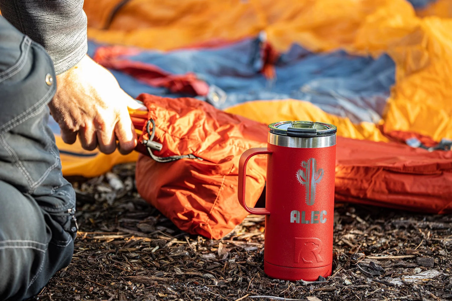 laser engraved rtic travel tumbler in outdoor setting.  Engraving shows name and an image of a cactus