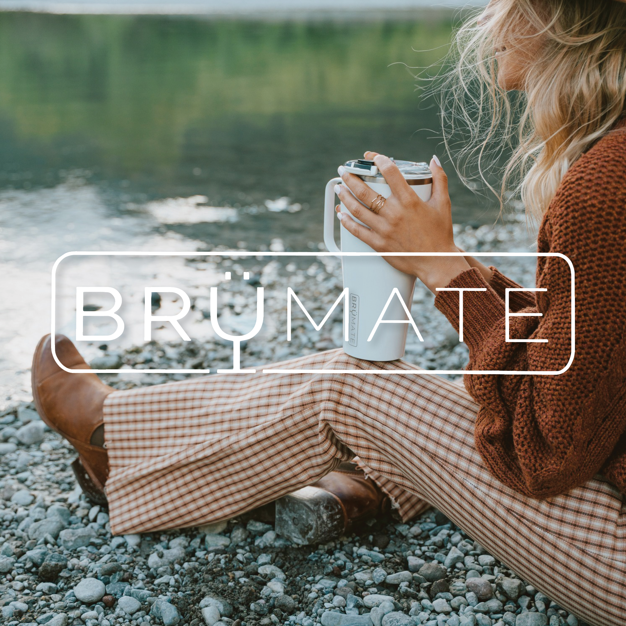 Woman sitting on rocks in front of lake while holding white Brumate Toddy XL Mug