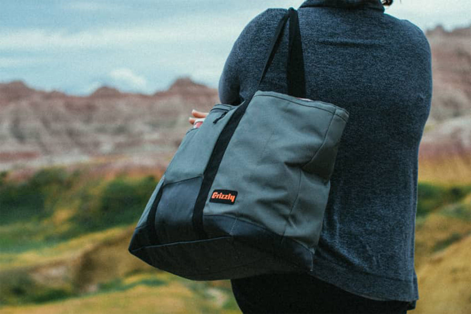 Woman holding a Grizzly Drifter Carryall Cooler Tote Bag while looking at mountains