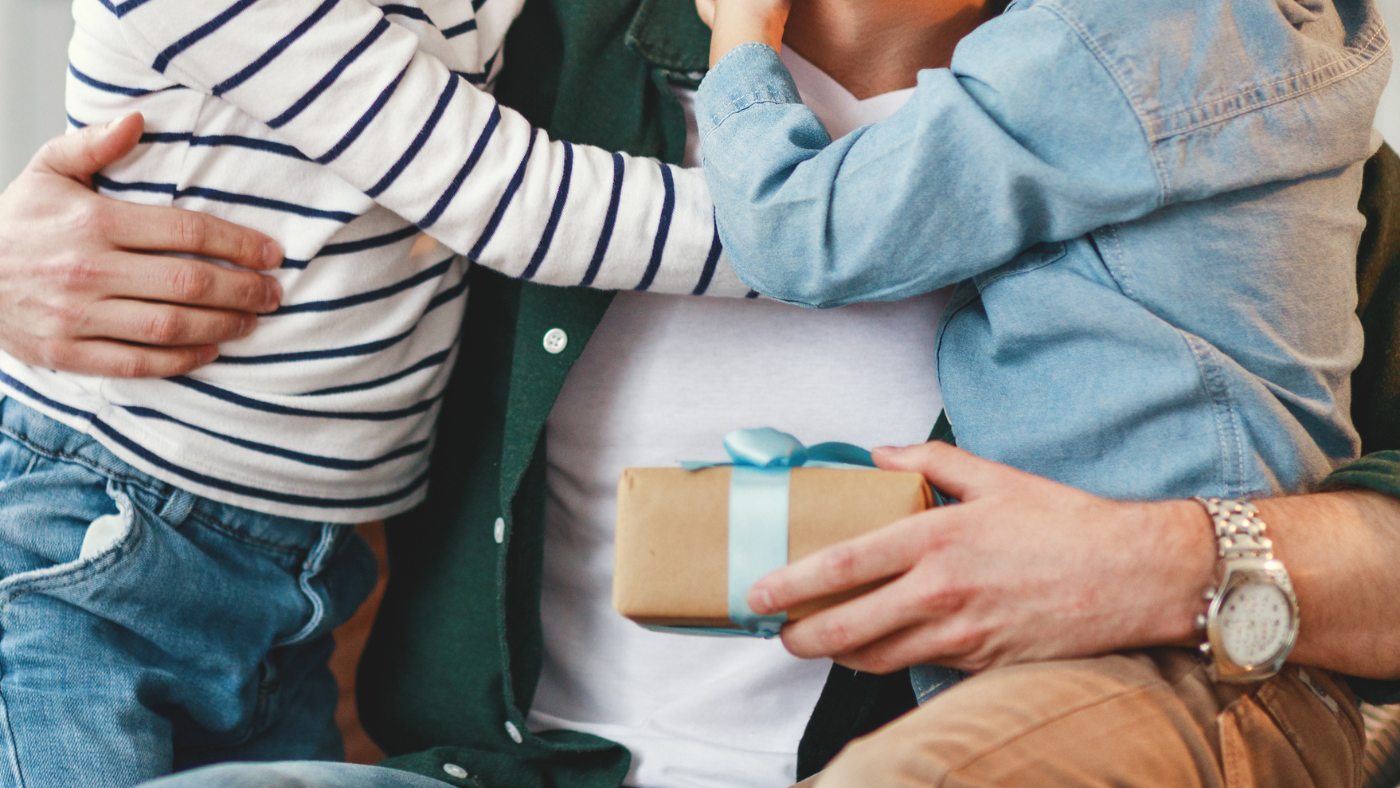 Dad holding two kids and a gift