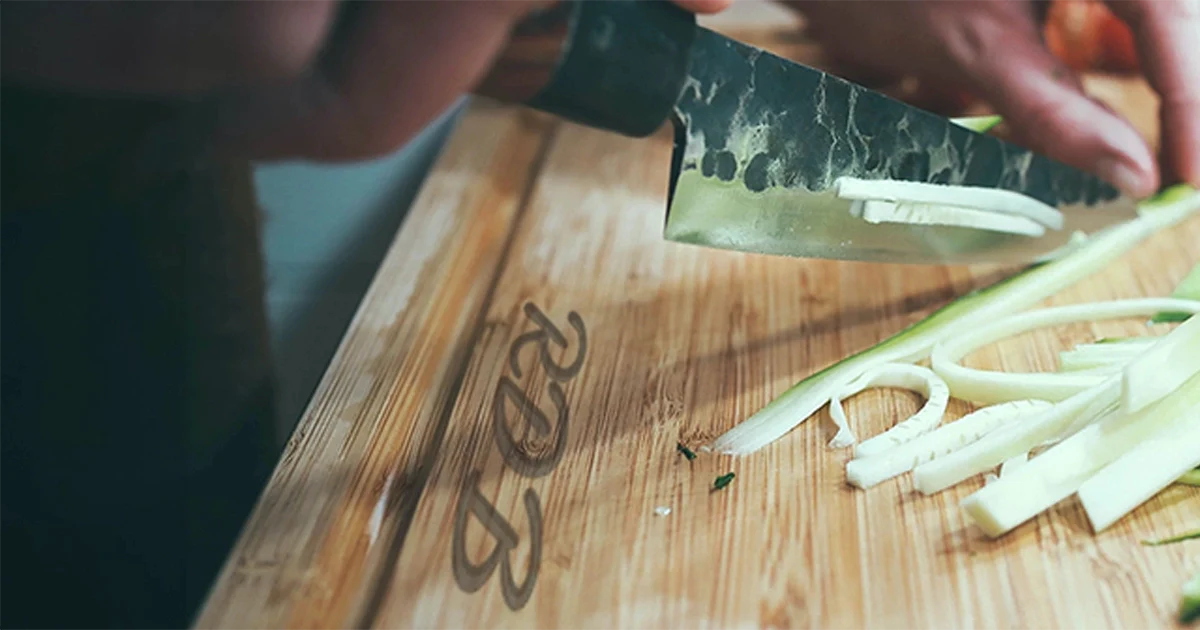 person chopping food on a personalized maple cutting board