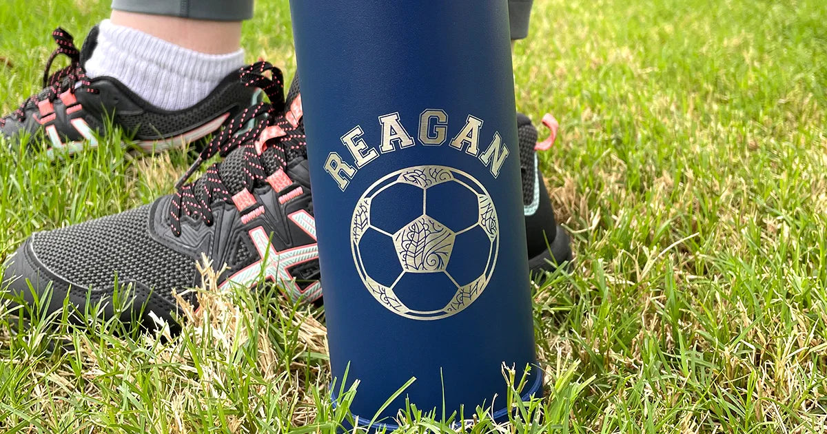closeup of an engraved water bottle.  Engraving shows personalized last name and a stylized soccer ball.