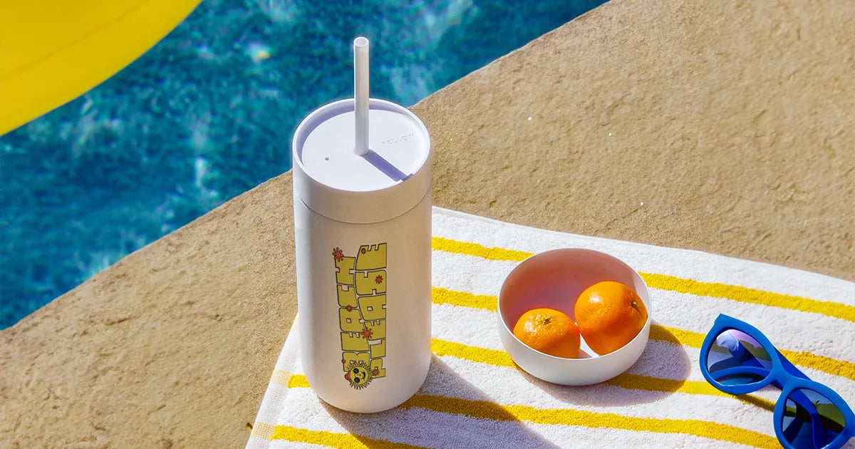 Custom straw tumbler with a sunshine print , sitting by a pool
