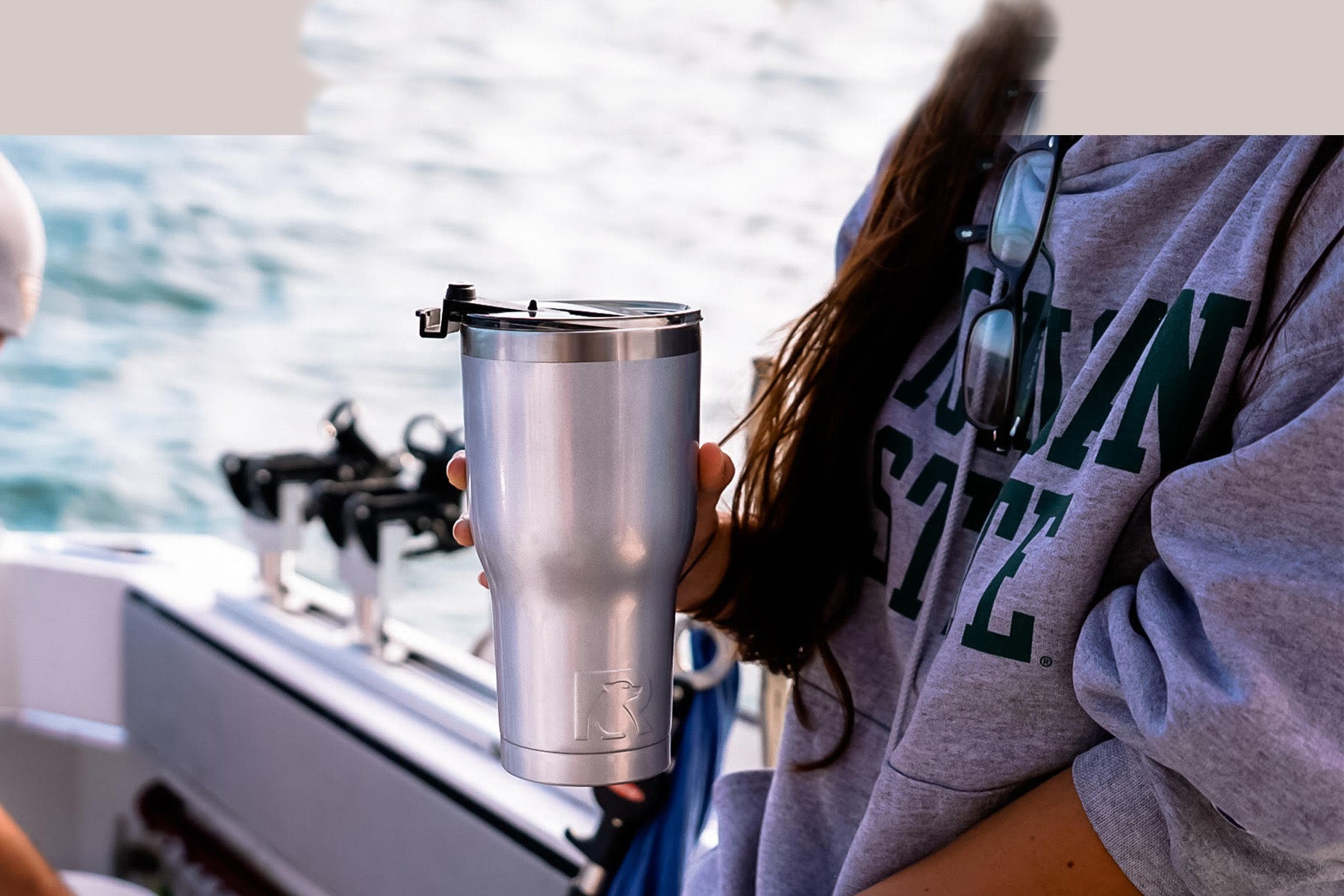 Woman holding silver RTIC 30 oz tumbler while on a boat.