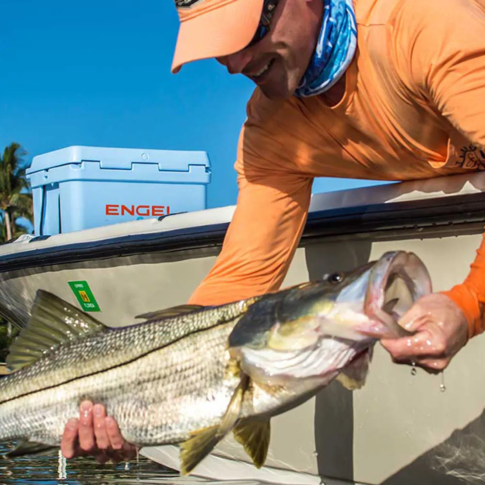 Man with fish in boat with Engel cooler in the background.