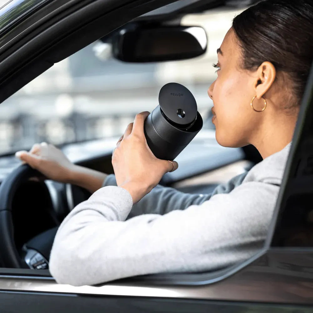 Woman dinking from Fellow Slide Mug while driving.