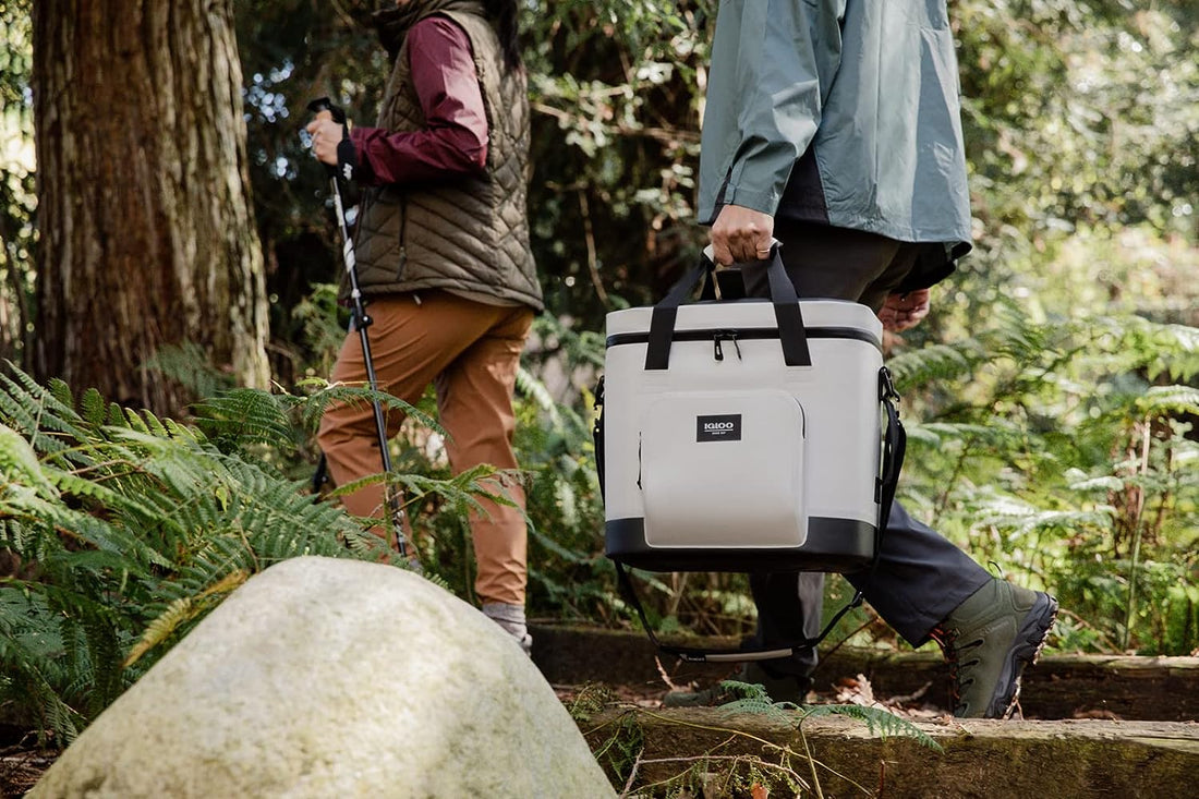 two people walking through the woods with a 30 can igloo trailmate soft cooler