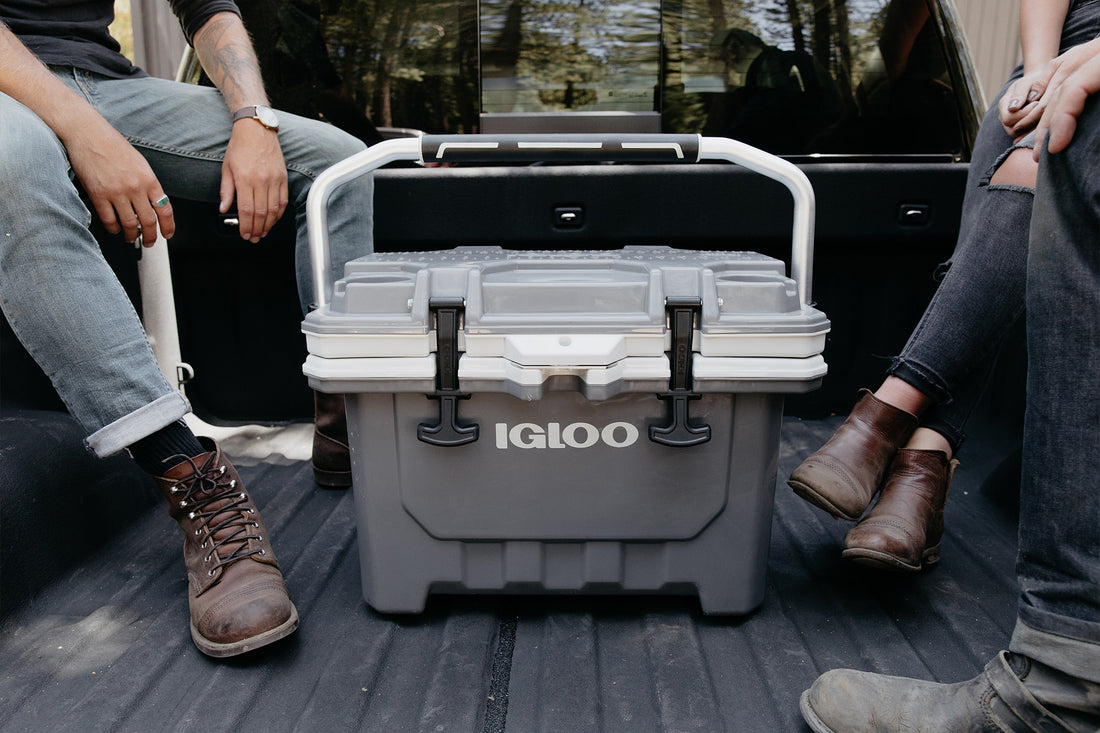 People sitting in bed of truck with gray Igloo IMX Cooler 24 Quart that has a handle