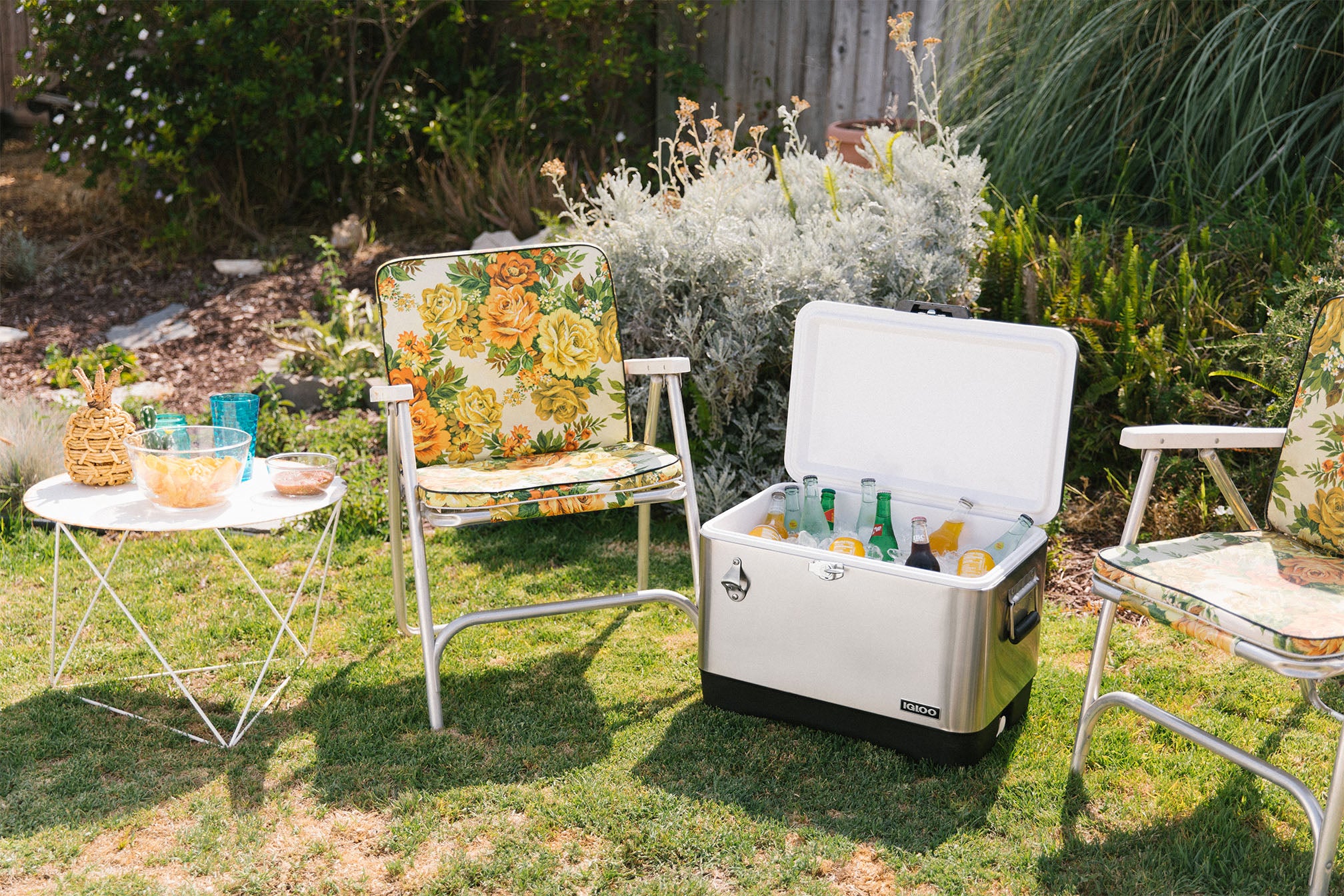 Backyard setting with two chairs and an Igloo Legacy 54 quart cooler filled with drinks.