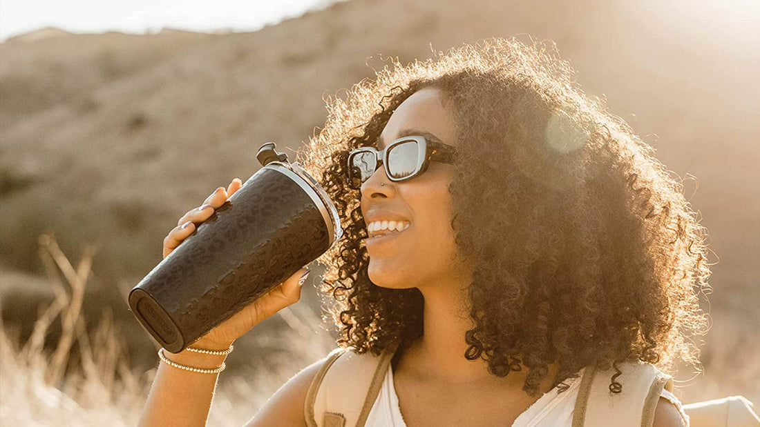 Woman drinking from Black Cheetah Print Toddy XL outside in the sun.