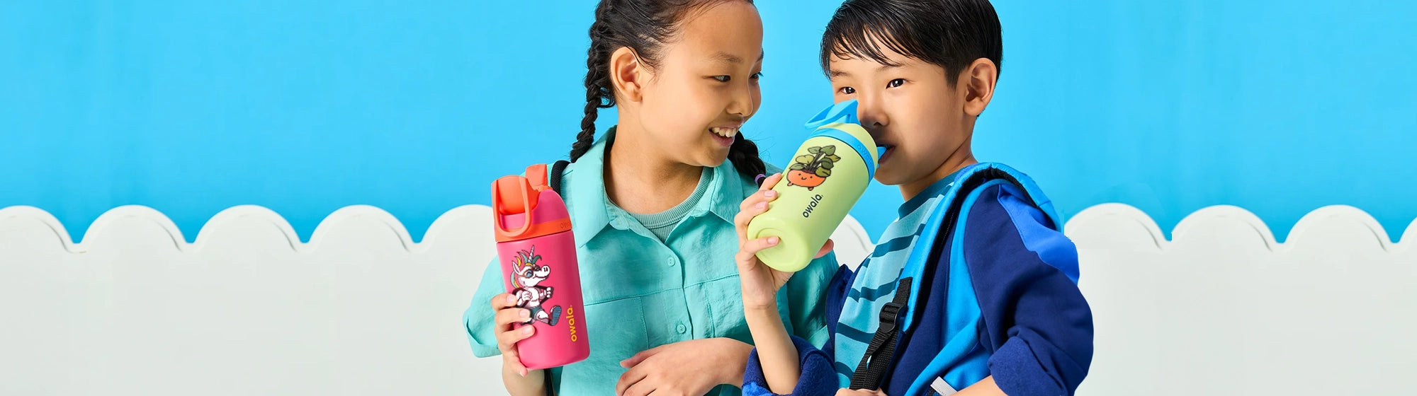 two kids drinking from owala freesip kids straw bottles. Straw bottles have a personalized color print.