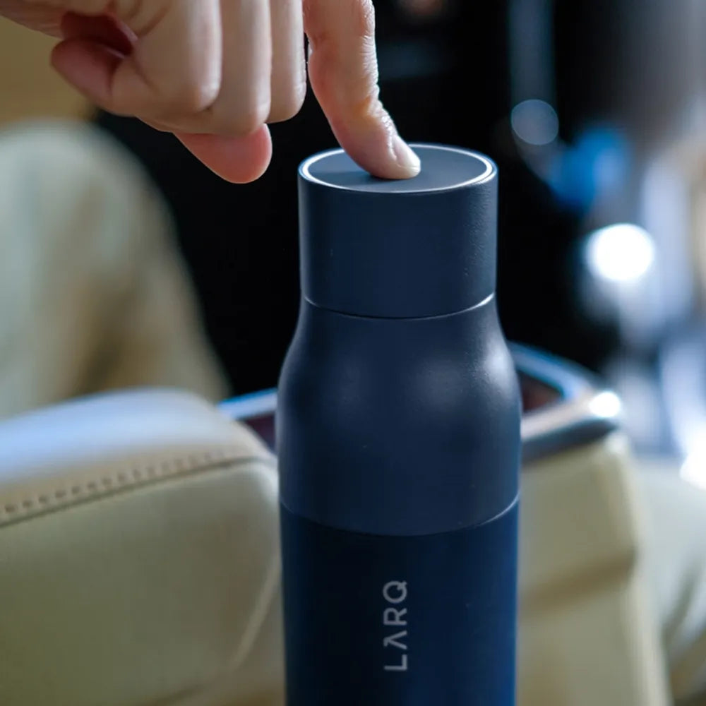 Person pushing the button to use UV Light on 17  oz Larq PureVis Self Cleaning Water Bottle. 