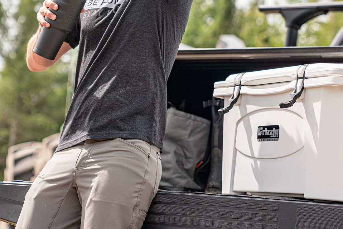 Man leaning against truck bed next to white Grizzly cooler 75 qt