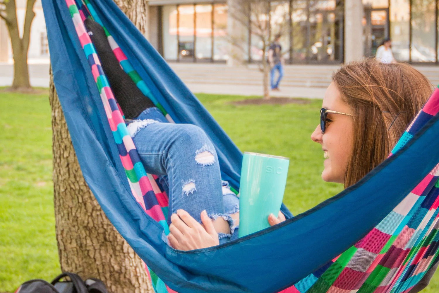 Girl in hammock holding seafoam blue SIC tumbler