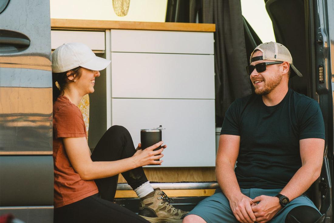 Couple sitting in travel van with girl holding black travel Orca Chaser tumbler