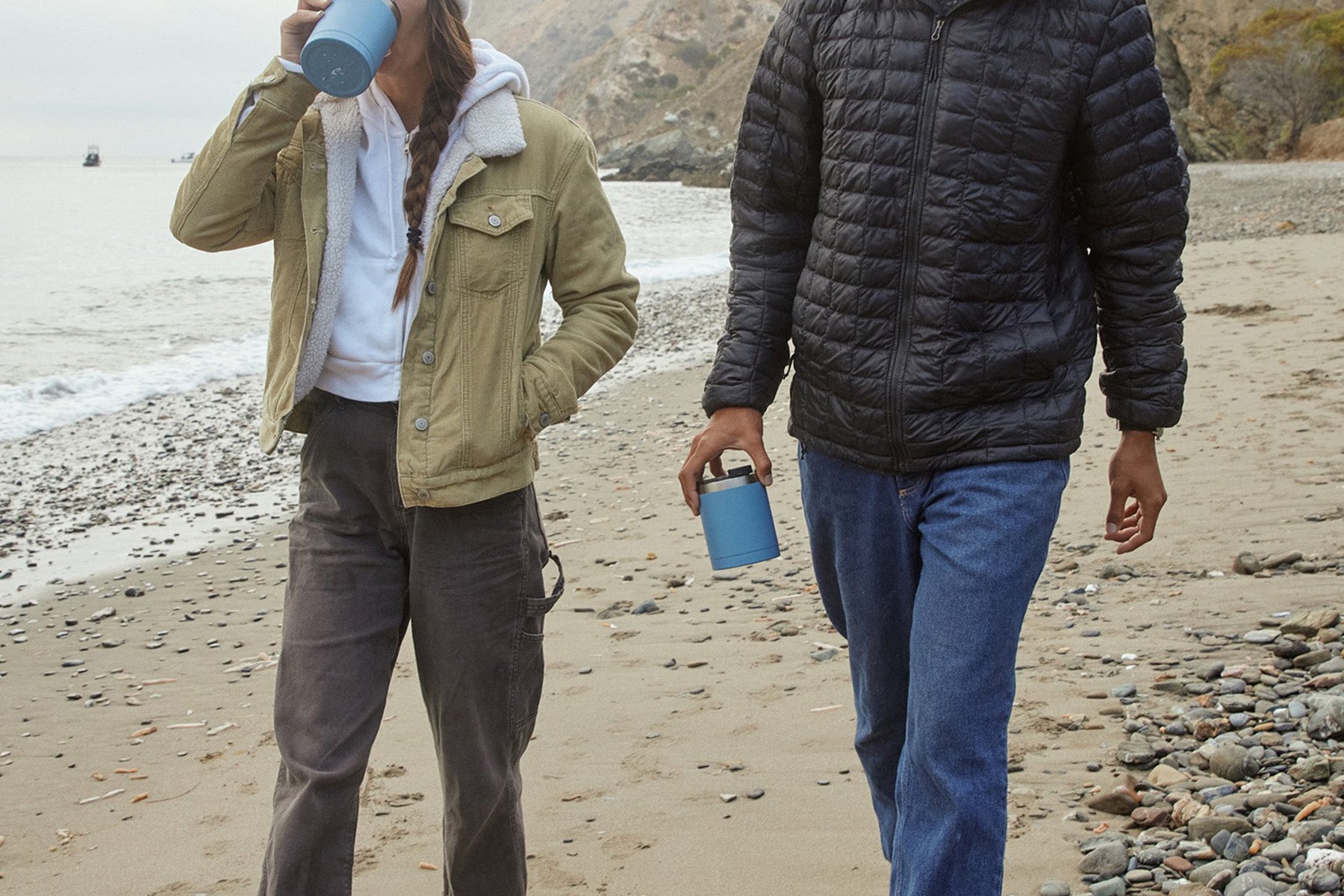 Couple walking on the beach while drinking from RTIC lowball tumbler in blue