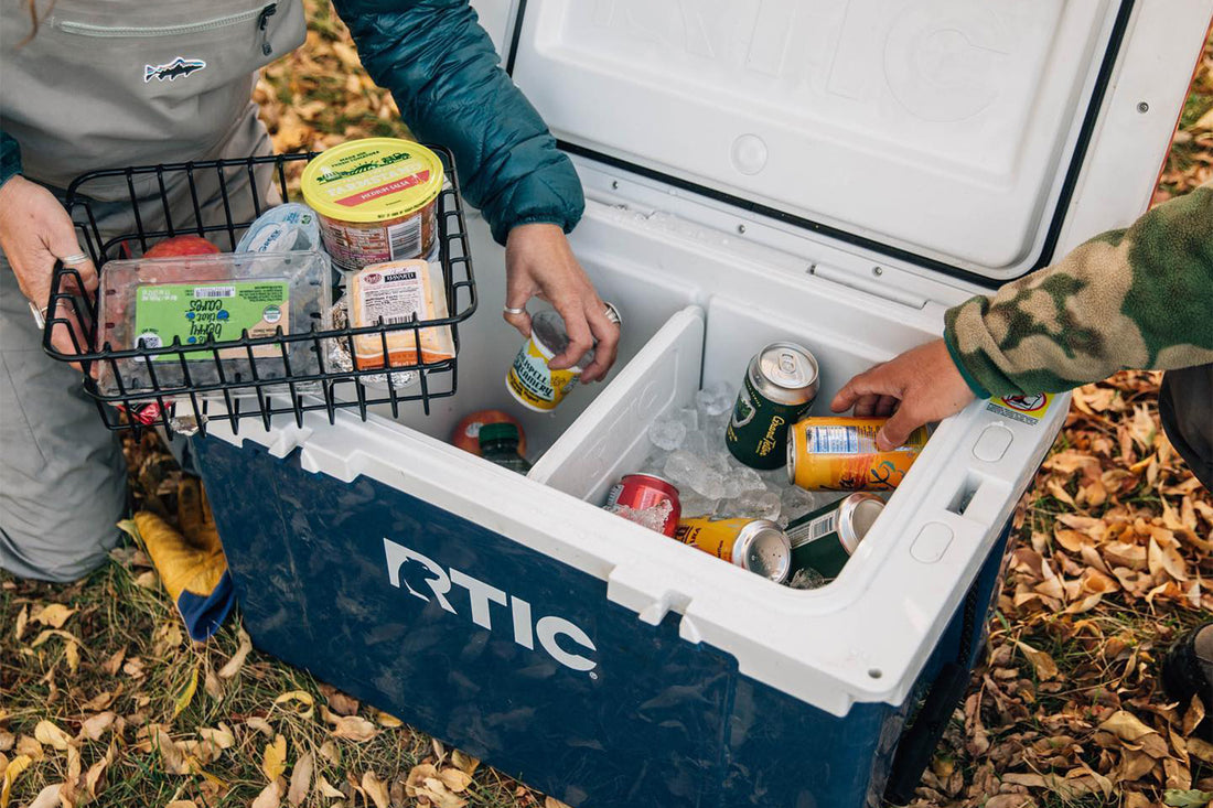 Two men unpacking cooler in the woods. RTIC Ultra Light Cooler 52 QT in Navy.