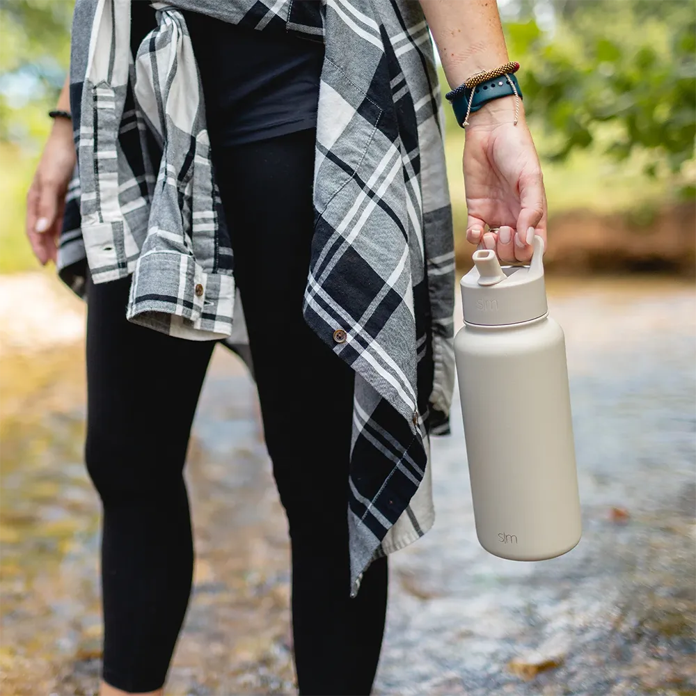 Woman holding Summit Water Bottle 32 ounce with straw lid in almond birch.