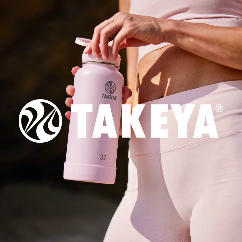 Woman in pink workout attire holding a matching pink takeya water bottle with flip lock spout lid and boot.  Offered customized from custom branding