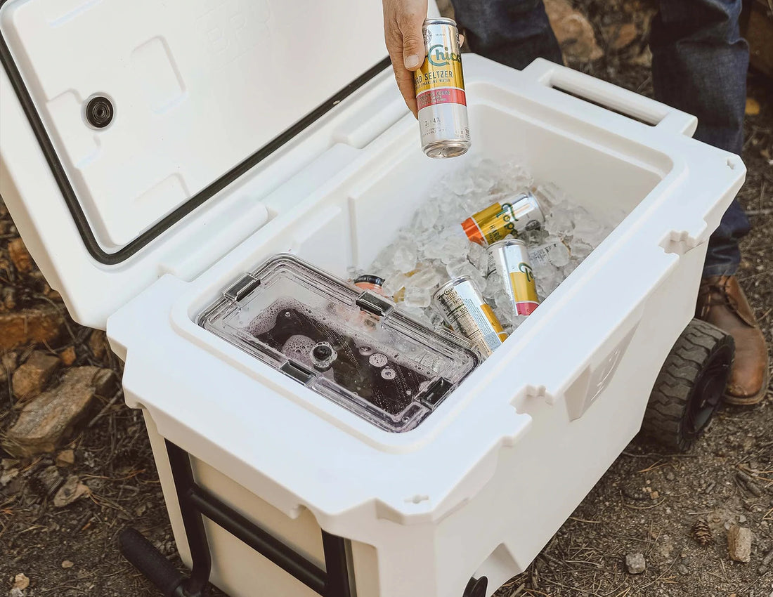 White Brumate Brutank hard sided cooler with lid open and man grabbing drink