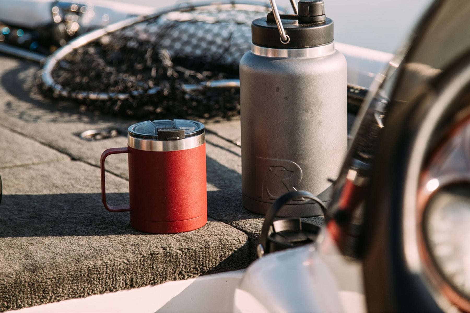 Red RTIC mug and gray RTIC water jug sitting on boat dock