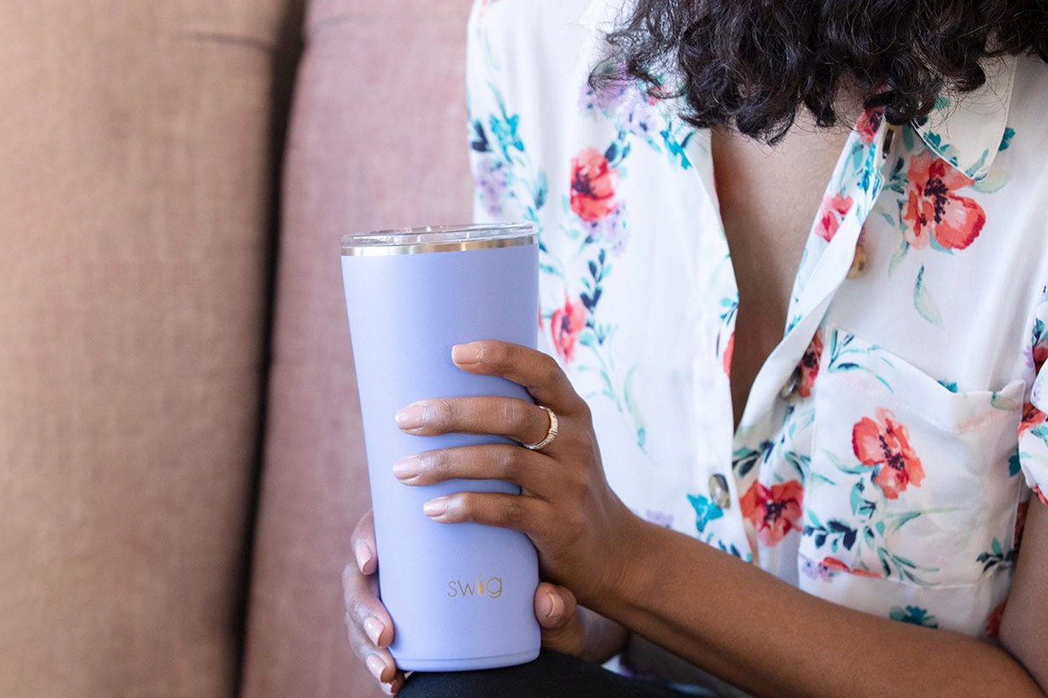 Woman in flower shirt holding purple Swig tumbler