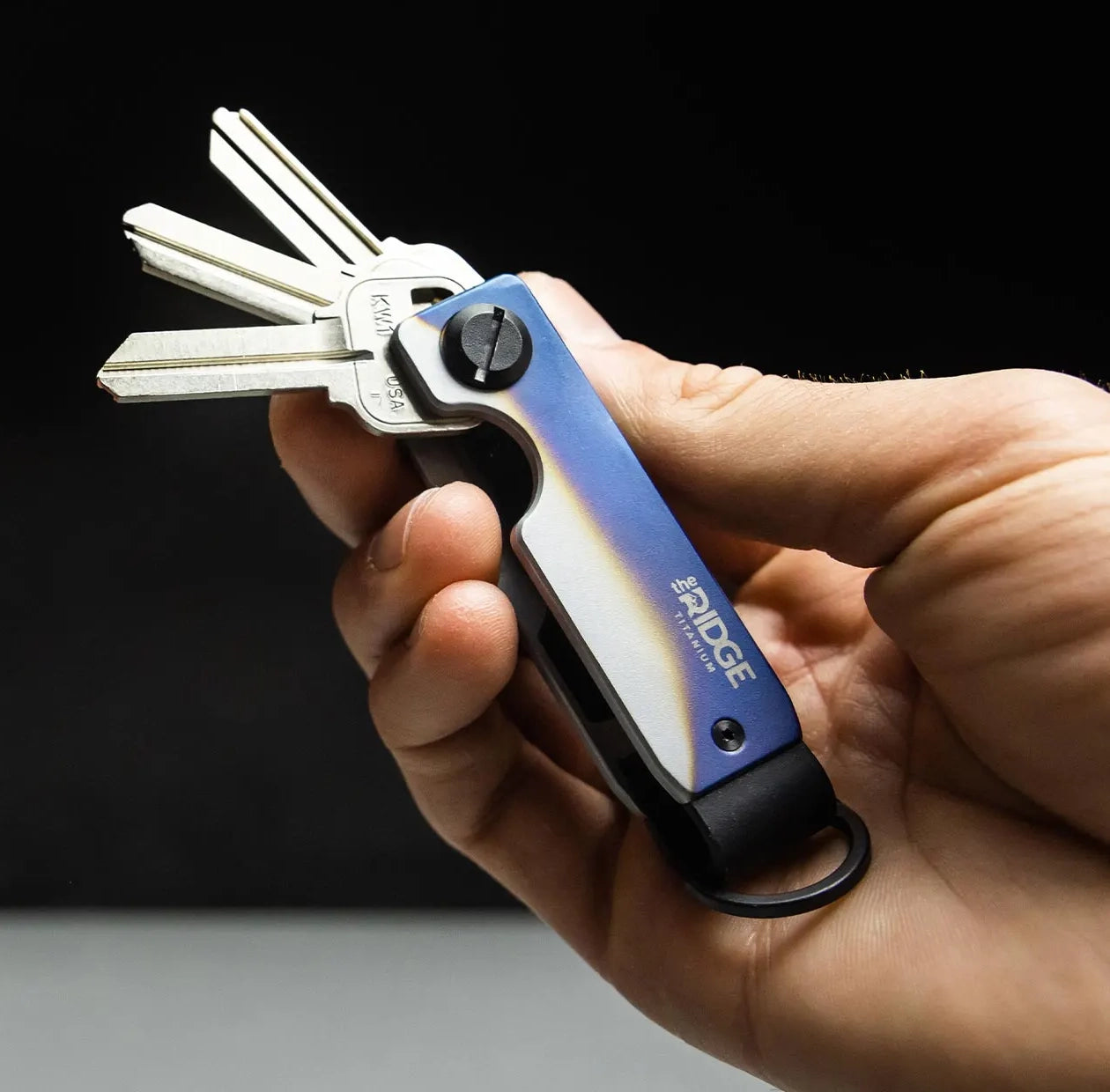 Image of a hand holding an un-customized key case key ring from The Ridge