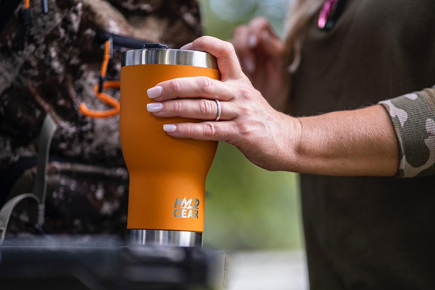 Woman holding orange Wyld Gear tumbler