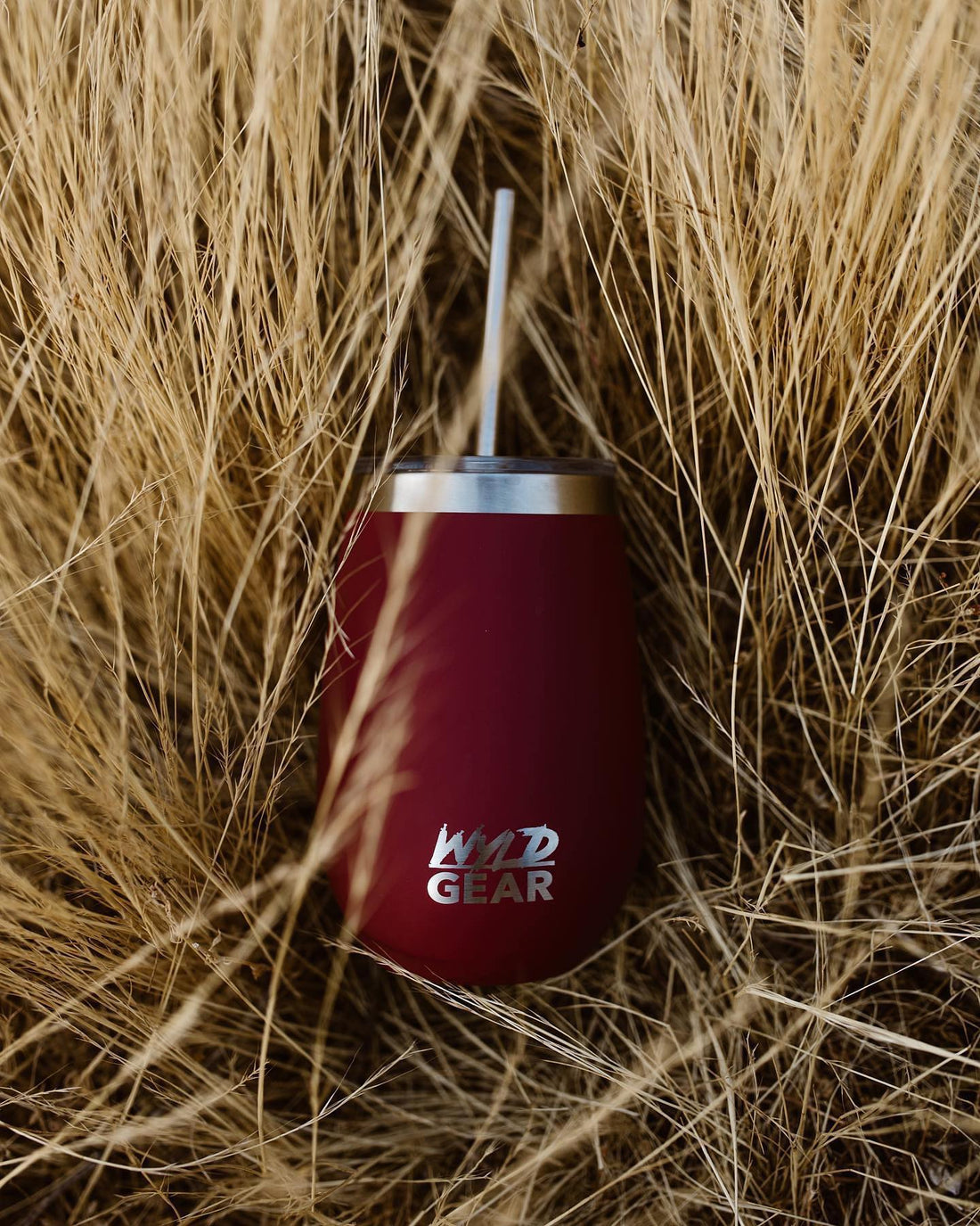 Red Wyld Gear wine tumbler sitting in tall grass